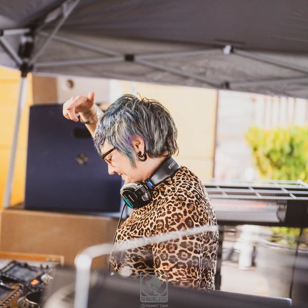 Jen Woolfe dancing at the decks in a leopard-print jacket