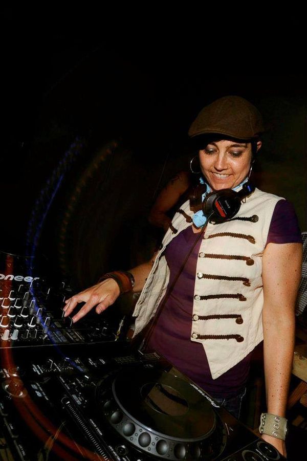 Jen Woolfe in a cap and military-style vest, smiling at the decks