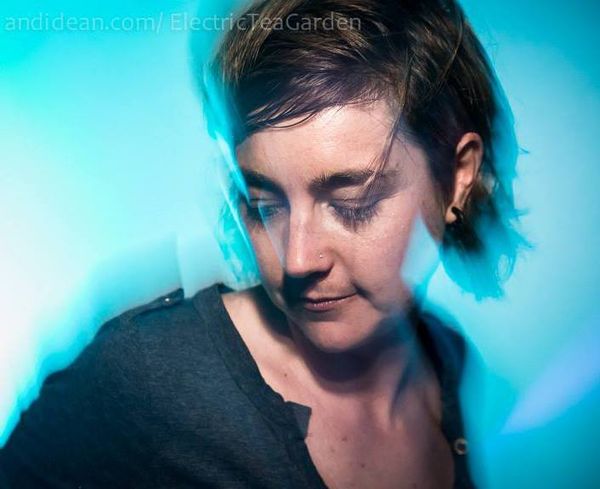 Portrait of Jen Woolfe looking down, lit in blue