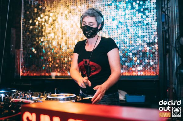 Jen Woolfe in a mask at the decks in front of a sequin wall