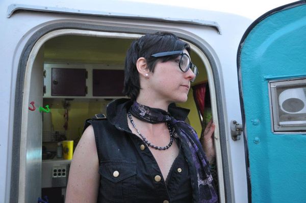 Jen Woolfe in a denim vest looking out of a turquoise trailer